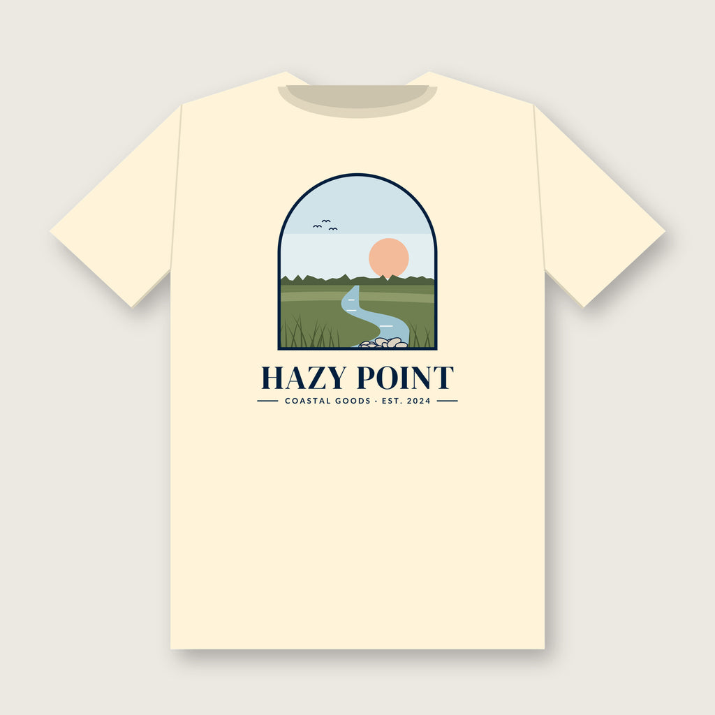 Back of the ivory Hazy Point Spartina Window Tee: an arched window looking onto spartina marsh grass, a winding tidal creek and a low sun, above the HAZY POINT wordmark and EST. 2024