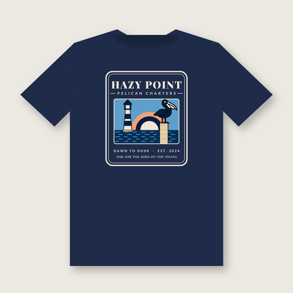 Back of the true navy Hazy Point Pelican Charters Tee: a pelican on a piling beside a striped lighthouse under an arc of sunrise, captioned like a charter office sign