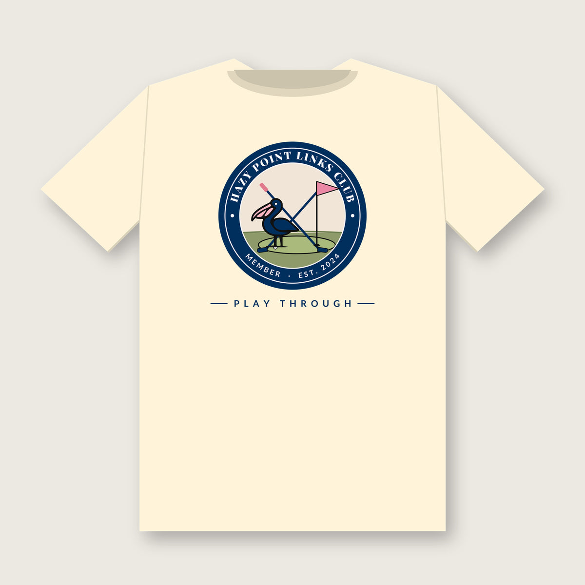 Back of the ivory Hazy Point Links Club golf tee: a navy ring crest reading HAZY POINT LINKS CLUB, MEMBER, EST. 2024 around a pelican on a putting green beside a pink pin flag and crossed golf clubs, with PLAY THROUGH beneath