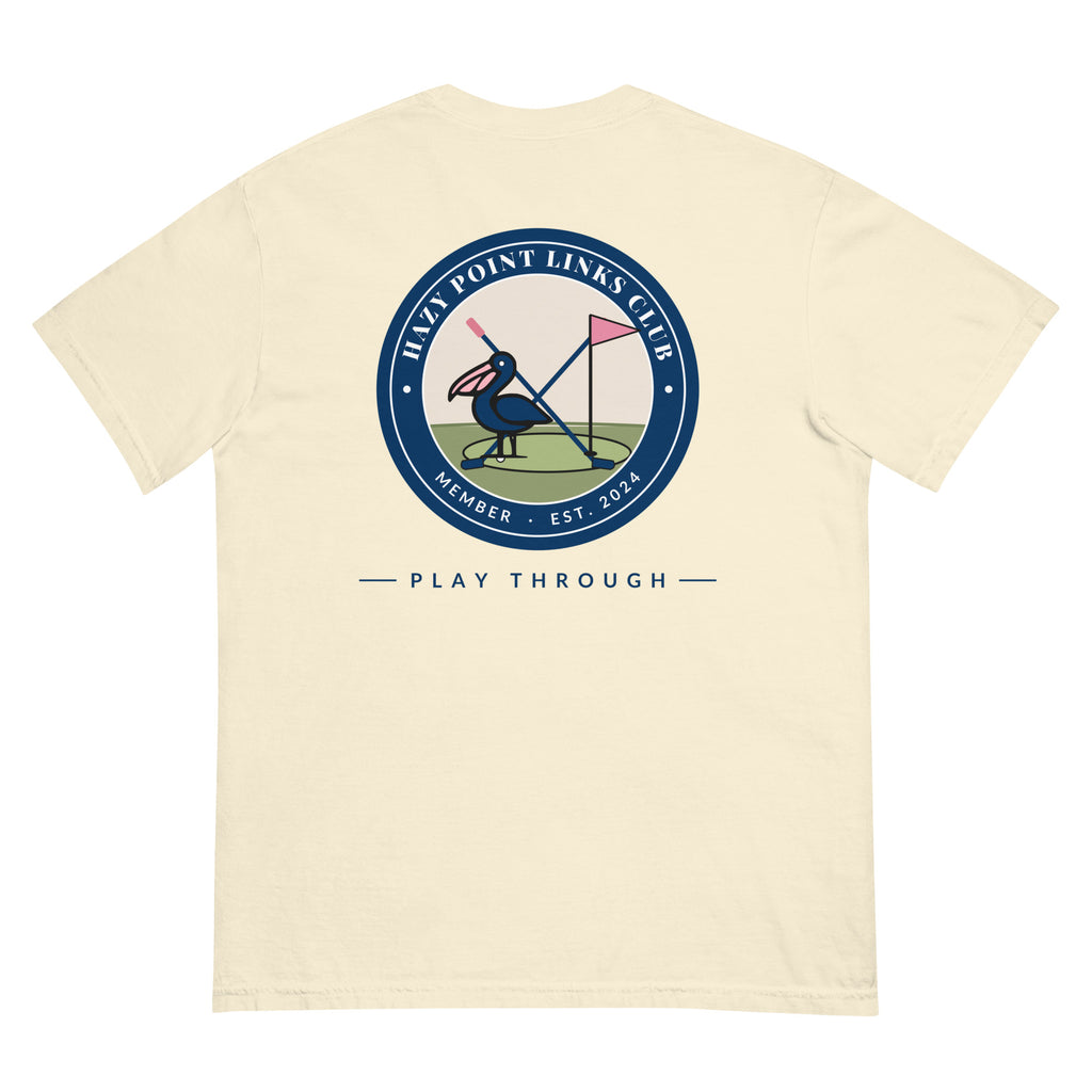 Back of the ivory Hazy Point Links Club golf tee: a navy ring crest reading HAZY POINT LINKS CLUB, MEMBER, EST. 2024 around a pelican on a putting green beside a pink pin flag and crossed golf clubs, with PLAY THROUGH beneath