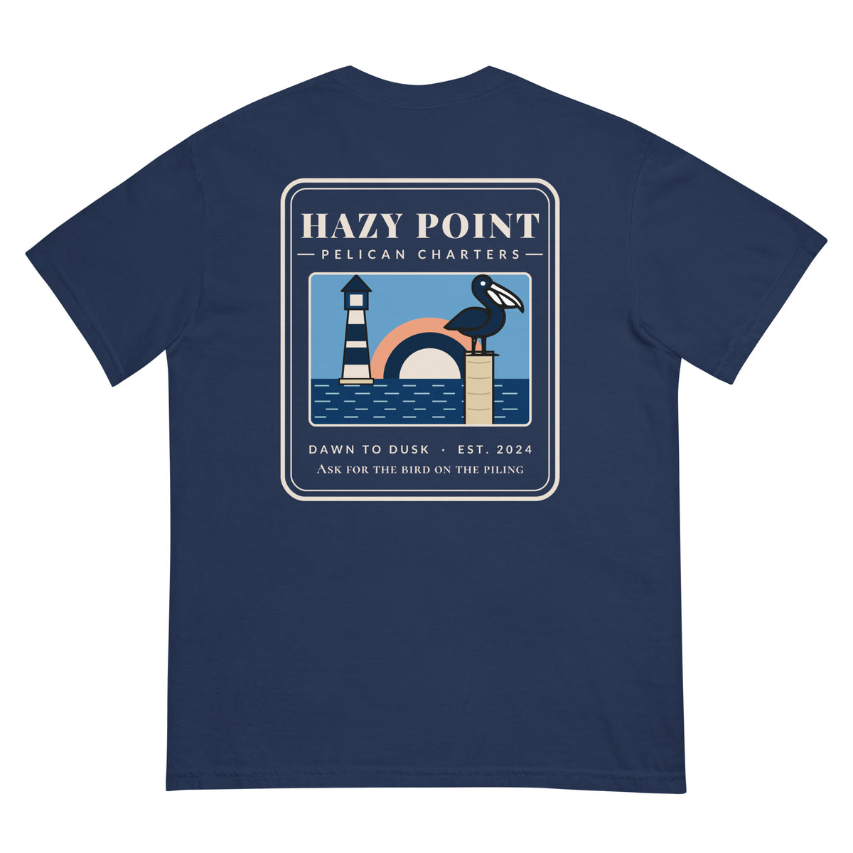Back of the true navy Hazy Point Pelican Charters Tee: a pelican on a piling beside a striped lighthouse under an arc of sunrise, captioned like a charter office sign